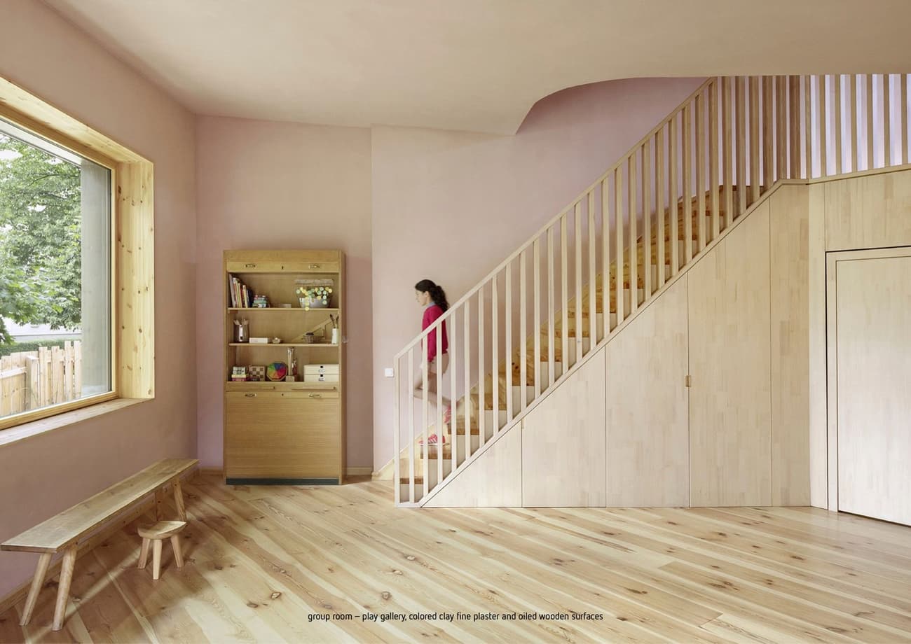 Architectural project - pastel pink, indoor space, natural materials, wooden bench, pink, wood, natural light, warm tones, neutral tones, beige, light wood, eco friendly, modern design, simple design, natural textures, Scandinavian style, eco materials, natural finish, cozy vibe, inviting home, large window, plaster, wooden interior, family space, warm atmosphere, bright interior, interior design, playful space, playroom, children's room, light wood flooring, wooden stairs, minimalist shelving, pastel walls, kid friendly, sustainable interior, residential area, wood frame window, plywood details, soft colors, residential use, relaxed space, wooden furniture