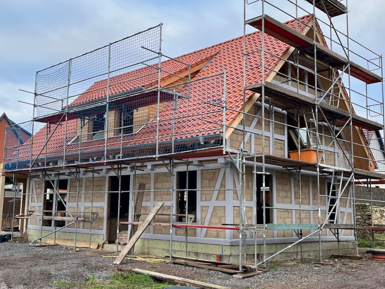 Architectural project - facade, brick wall, terracotta roof, classic design, masonry, renovation project, building restoration, half-timbered house, natural materials, wood, timber, scaffolding, timber frame, sustainable design, eco design, grey, neutral tones, exposed beams, carpentry, building site, beige, low carbon design, farmhouse style, outdoor, vernacular architecture, exterior, sustainable building, circular construction, natural ventilation, wood frame, stone, pitched roof, terracotta, brick, stone wall, rustic architecture, craftmanship, gable roof, countryside house, residential building, traditional house, construction, rural house, red