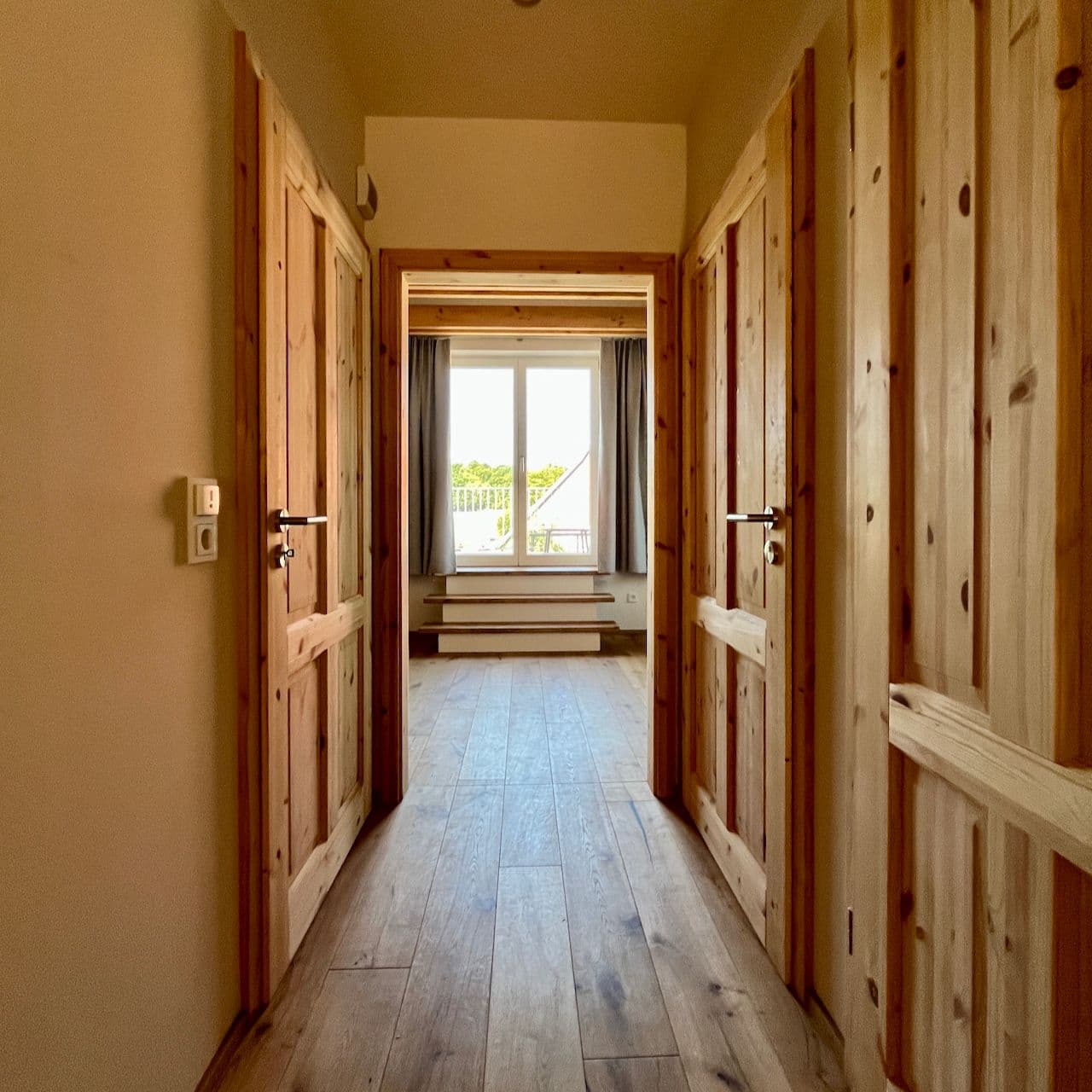Architectural project - beige walls, wooden doors, wooden features, comfort, cozy entrance, quiet space, simplicity, neutral walls, wood, timber, natural light, rustic touch, sustainable design, neutral tones, daylight, beige, light wood, natural wood, sunlight, simple design, rustic vibe, Scandinavian style, timber floor, wooden floor, eco-friendly materials, light tones, timber panels, Nordic style, warm ambiance, wood texture, minimalist decor, wooden panels, residential space, timeless design, home interior, cozy home, hallway, understated elegance, residential hallway, interior corridor