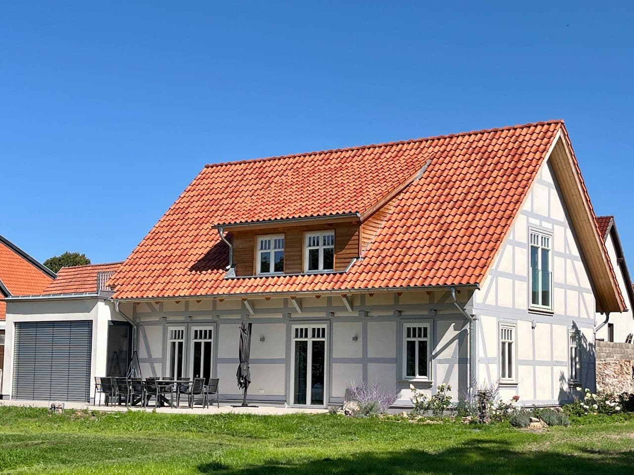 Architectural project - peaceful home, energy-efficient home, suburban living, landscaped garden, farmhouse vibe, country charm, wood, timber, timber frame, natural light, passive design, green, natural setting, outdoor seating, eco-friendly materials, sustainable home, white facade, timber cladding, white, rural home, countryside home, plaster, rustic style, clay, pitched roof, brick, quiet retreat, countryside, garden view, gable roof, cozy exterior, rural charm, family home, inviting exterior, patio area, outdoor dining, traditional house, natural surroundings, home renovation, red