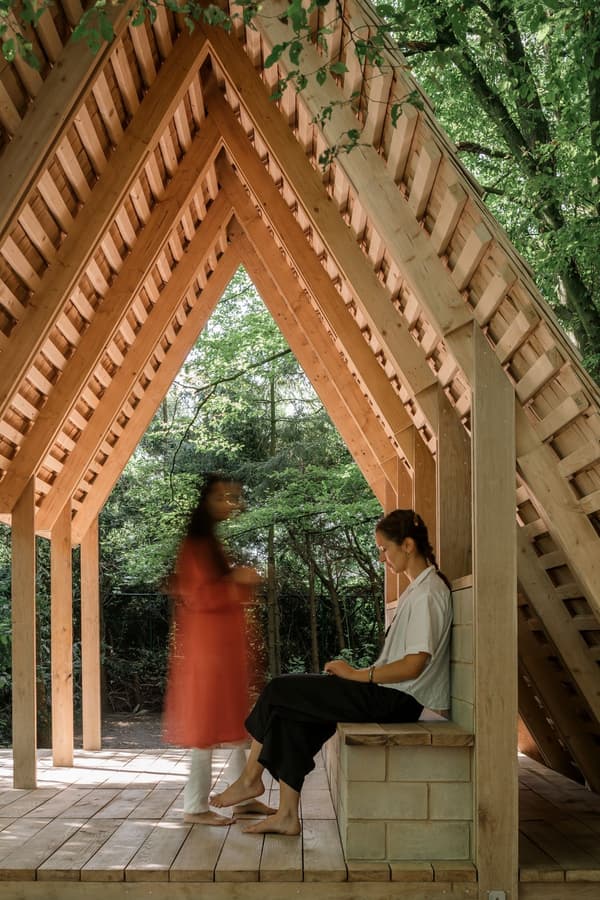 Architectural project - natural materials, wood, timber, outdoor space, natural light, passive design, warm tones, eco design, exposed beams, daylight, light wood, Scandinavian influence, natural setting, wooden beams, timber construction, rustic charm, serene atmosphere, minimalist design, open framework, wood structure, sustainable building, green architecture, biophilic design, timber cladding, harmonious design, cozy nook, textured wood, earthy tones, pitched roof, treehouse, forest retreat, triangular roof, tranquil vibe, peaceful escape, simple living, nature connection, earthy elements, quiet retreat, relaxing space, outdoor seating area, contemplative space, environmentally friendly, wooden seating