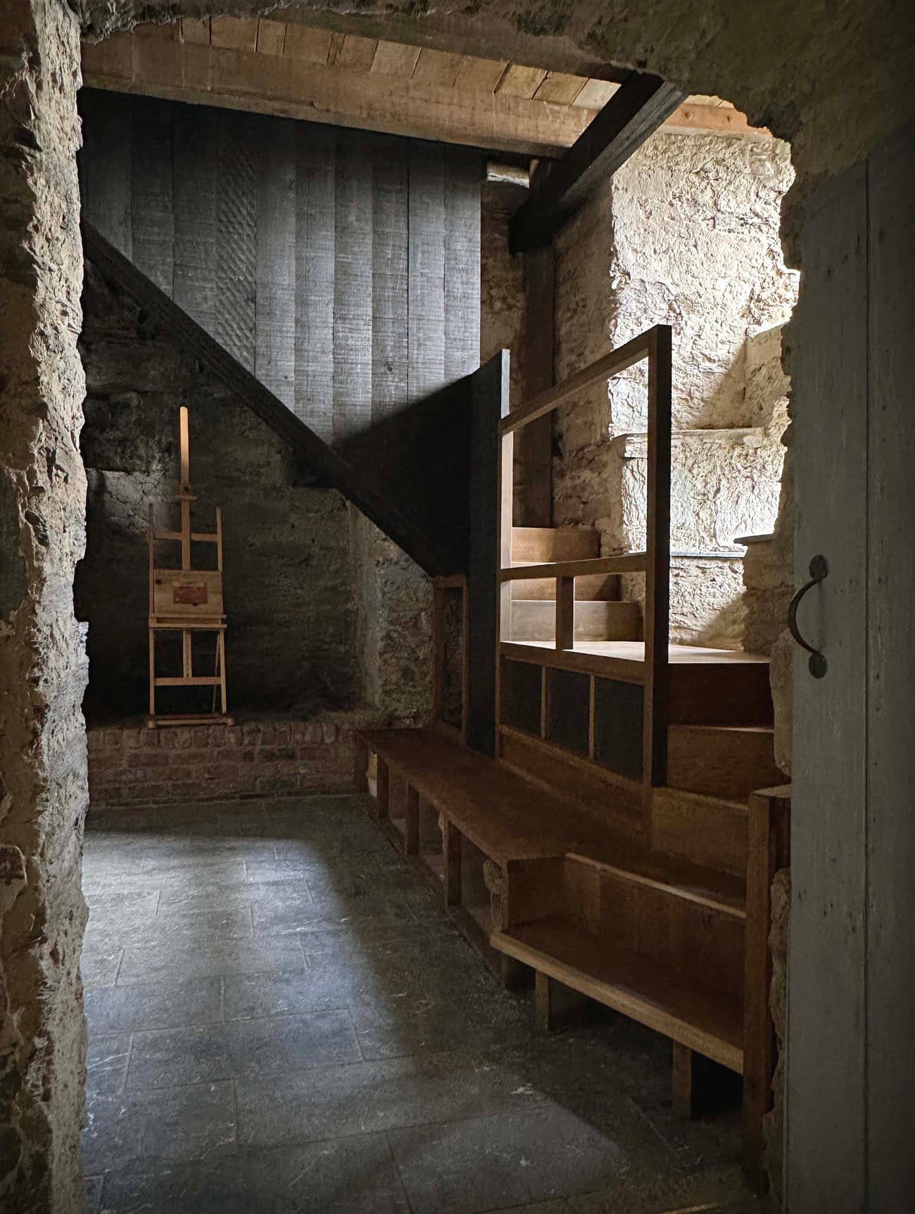 Architectural project - workshop space, exposed stone, historical restoration, raw textures, rustic bench, homely space, rustic finishes, rustic interior, vintage style, earthy design, stone construction, medieval style, vintage charm, traditional craft, rustic stairwell, timber stairs, stair railing, vintage chair, timber, raw materials, reclaimed materials, warm tones, beige, brown, natural textures, raw wood, earth tones, stone, rustic style, earthy tones, traditional design, stone wall, wooden seating, rustic architecture, cozy corner, textured walls, rustic aesthetic, warm lighting
