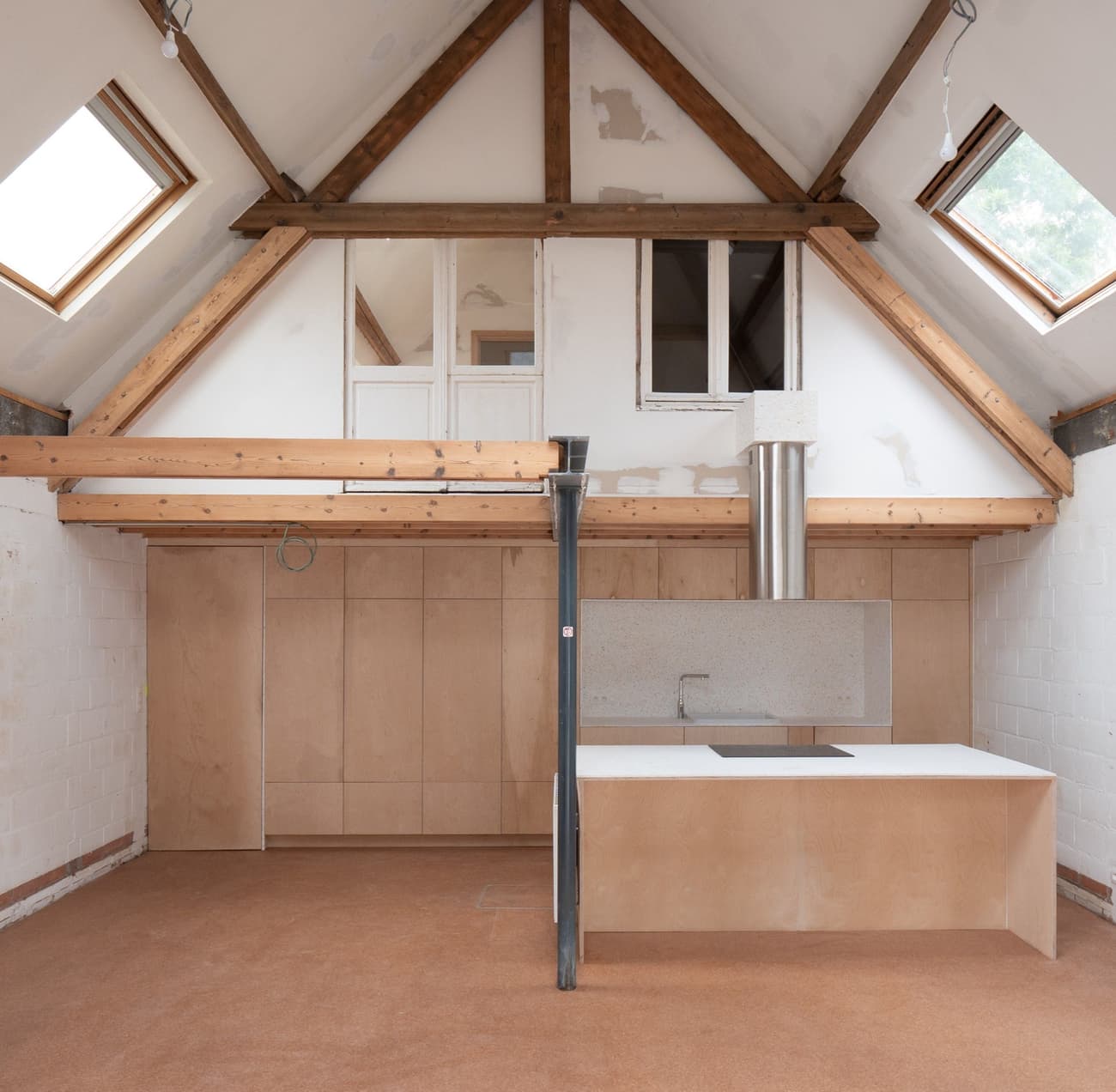Architectural project - plywood walls, skylights, attic renovation, loft conversion, renovation project, multipurpose space, warm floor, architectural detail, sustainable materials, natural light, passive design, sustainable design, neutral tones, exposed beams, daylight, beige, brown, truss structure, light wood, timber beams, rustic modern, industrial touch, Scandinavian style, minimalist design, wood floor, wood panels, modern rustic, clean lines, white, Nordic design, eco friendly home, small space, warm ambiance, open plan, earthy tones, bright interior, functional layout, kitchen island, compact kitchen, plaster walls, modern living, cozy home, eco renovation, vaulted ceiling
