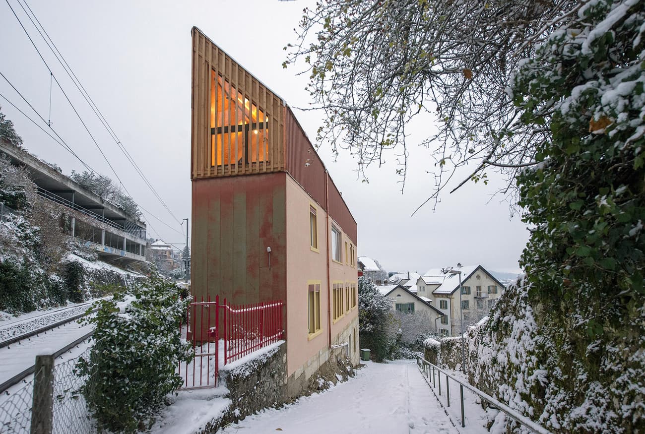 Architectural project - beige facade, urban residential, warm glow, red accent, insulated walls, colorful facade, countryside feel, rustic elements, hillside home, pastel pink, pastel tones, pink, wood, timber, natural light, sustainable design, warm tones, neutral tones, beige, concrete, wood facade, timber facade, eco friendly, rustic charm, minimalist design, eco materials, modern rustic, natural ventilation, scenic view, energy efficient, plaster, cozy exterior, residential home, passive solar, family house, urban architecture, architectural contrast, small windows, red