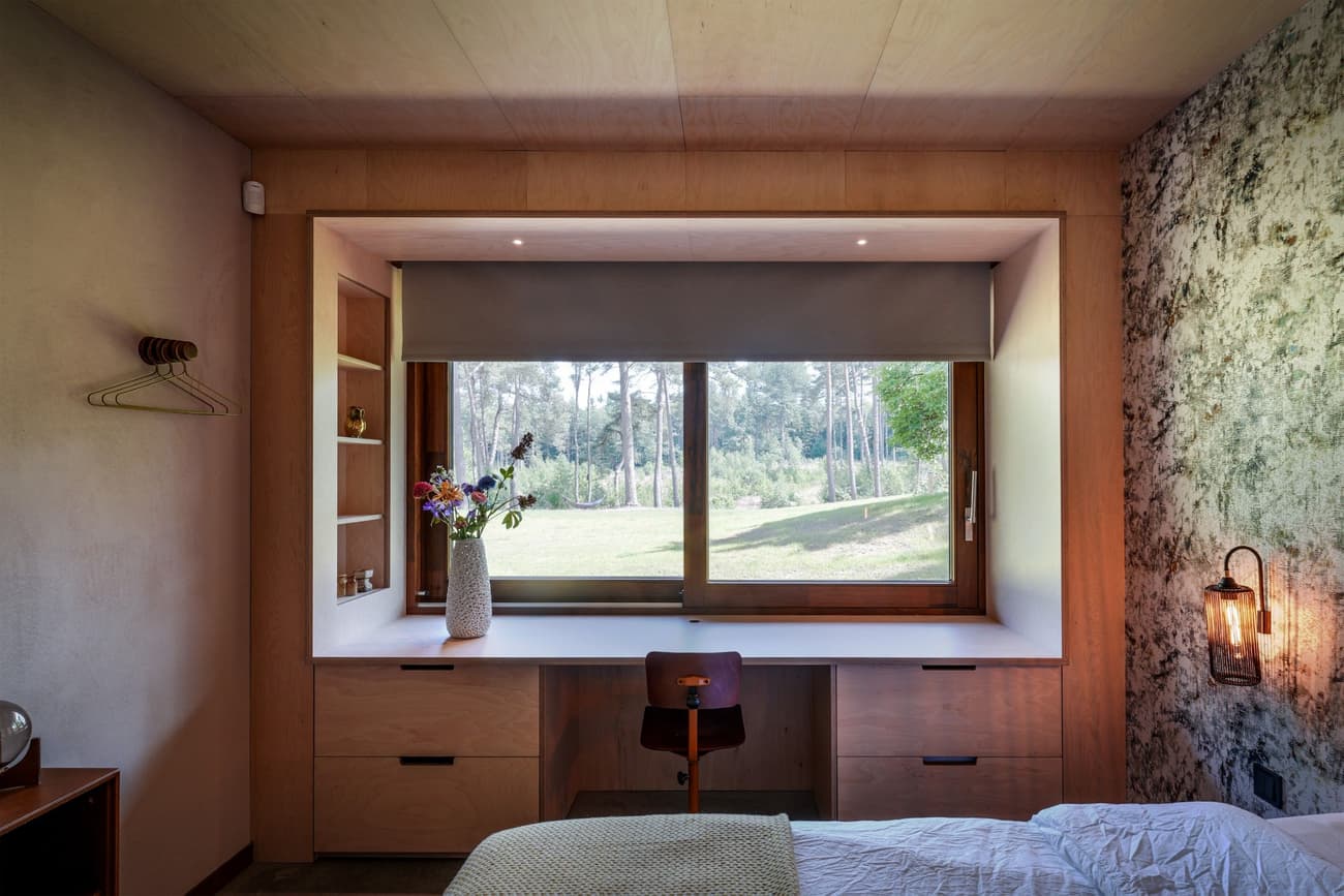 Architectural project - wood wall, modern lamp, plywood walls, ceiling light, bedroom, wooden desk, compact room, writing desk, built-in desk, peaceful room, flower vase, wall lamp, bedside light, wooden chair, desk chair, relaxation space, natural materials, wood, timber, natural light, sustainable design, glass, warm tones, eco design, green, functional space, plywood, beige, brown, modern design, rustic modern, calm ambiance, private retreat, Scandinavian style, minimalist style, neutral palette, workspace, modern rustic, biophilic design, passive house, natural ventilation, nature view, white, cozy vibe, Nordic style, large window, textured wall, stone, minimalist decor, earthy tones, nature-inspired, stone wall, relaxing space, garden view, home office, simple decor, timber wall, cozy bedroom, indoor plant