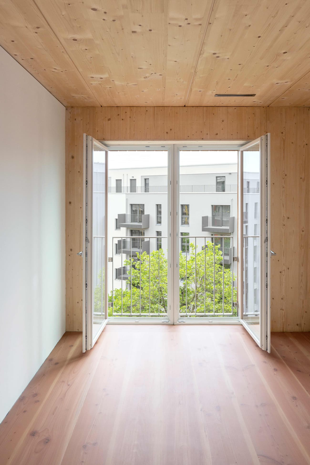 Architectural project - open doors, balcony view, apartment interior, French doors, sustainable materials, wood, timber, cityscape, natural light, sustainable design, eco design, green building, contemporary style, neutral tones, daylight, light wood, natural wood, eco friendly, simple design, honey wood, minimalist architecture, Scandinavian style, thermal comfort, biophilic design, passive house, clean lines, white walls, indoor outdoor, white, harmonious design, cozy vibe, Nordic style, relaxing space, timber flooring, minimalist space, residential space, fresh air, wood ceiling, interior space, airy atmosphere, wood flooring, energy efficiency, modern interior, connection to nature, living space, wood interior, timber room, urban view, bright room, urban apartment