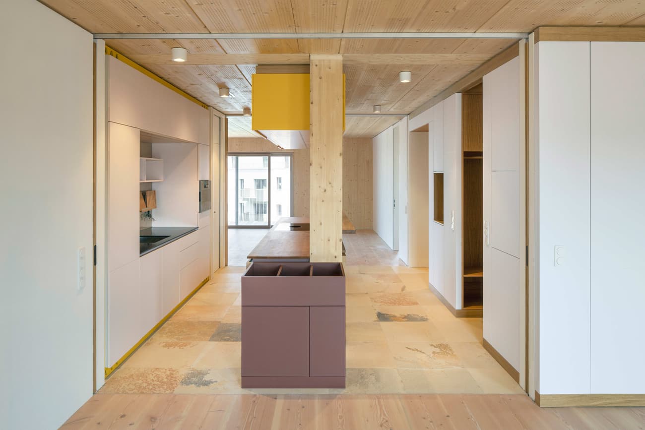 Architectural project - airy interior, modern cabinetry, open kitchen, integrated storage, tile flooring, architectural detail, wood, timber, natural light, sustainable design, yellow, warm tones, modular construction, neutral tones, daylight, beige, brown, light wood, eco friendly, Scandinavian influence, compact space, honey wood, wooden floor, minimalist design, exposed wood, passive house, clean lines, white walls, white, Nordic style, energy efficient, stone, timber ceiling, open plan, stone tiles, residential design, built-in shelves, modern kitchen, sleek design, functional layout, kitchen island, bright space, sliding doors, wood ceiling, contemporary vibe, wooden cabinetry, kitchen, spacious feel