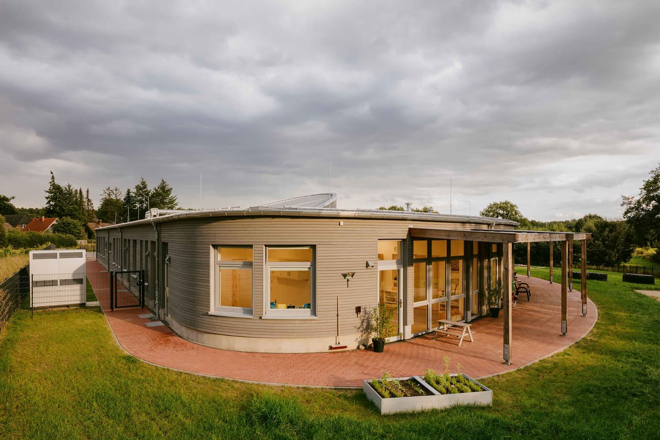Architectural project - floor to ceiling windows, pergola, patio space, terracotta tiles, horizontal cladding, suburban setting, wood, metal, outdoor space, natural light, sustainable design, glass, warm tones, eco design, contemporary architecture, grey, neutral tones, timber structure, daylight, beige, brown, concrete, flat roof, rustic vibe, minimalist design, glass doors, low carbon, passive house, modern facade, wood cladding, white, inviting home, energy efficient, compact design, green home, terracotta, garden view, nature integration, cozy exterior, residential home, family house