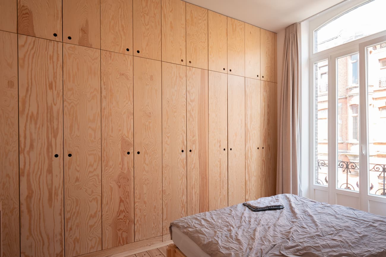 Architectural project - bedroom, calm vibe, modern bedroom, simple bedroom, city view, efficient storage, city apartment, minimal design, eco-friendly design, sustainable materials, natural light, daylight, plywood, beige, light wood, natural wood, functional design, compact space, minimalist style, neutral palette, cozy space, sustainable home, clean lines, Nordic design, large window, beige tones, warm atmosphere, relaxing space, peaceful vibe, Scandinavian design, timeless design, home design, soft tones, residential, clean design, built-in storage, clutter-free, modern interior, minimalist bedroom, light beige, urban living, bright room