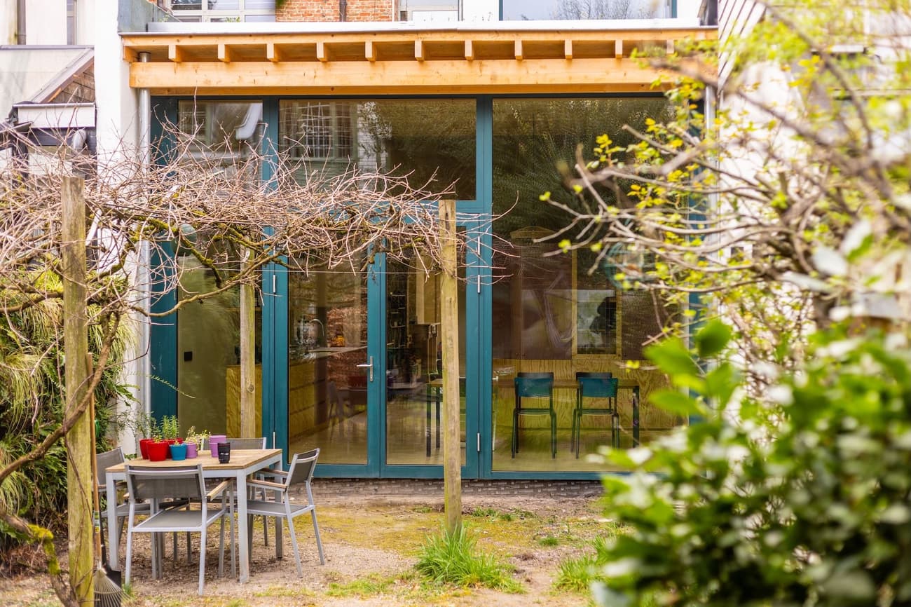 Architectural project - home extension, modern patio, garden furniture, folding chairs, backyard design, pergola design, outdoor oasis, minimalist outdoor, natural materials, wood, timber, metal, timber frame, natural light, outdoor living, glass, warm tones, eco design, contemporary style, grey, green, neutral tones, beige, daylight optimization, minimalist vibe, wood structure, sustainable building, green architecture, biophilic design, sustainable home, large windows, indoor outdoor, open plan, inviting space, alfresco dining, casual dining, cozy atmosphere, relaxed setting, garden view, residential architecture, bright interior, family home, modern home, patio area, outdoor dining, urban garden, glass facade