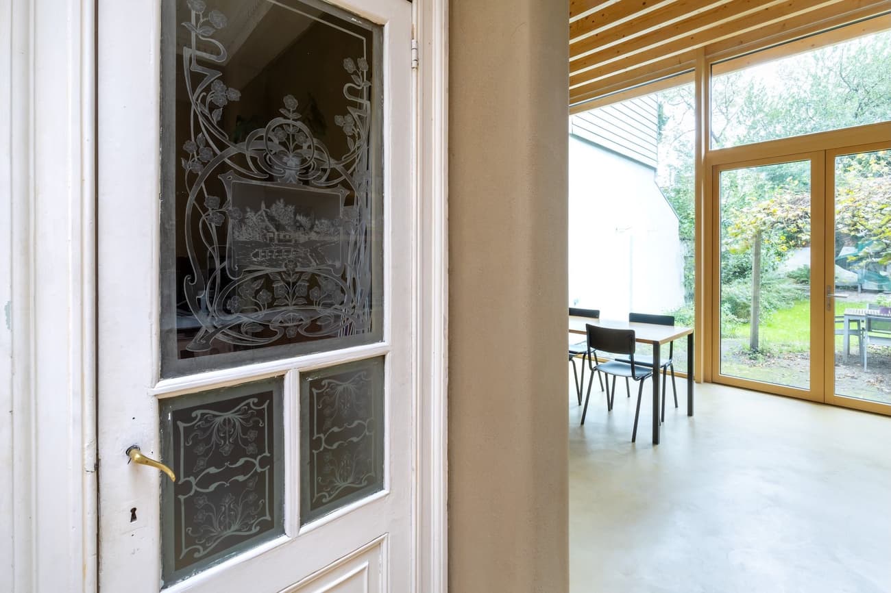 Architectural project - beige walls, airy interior, dining room, peaceful home, modern extension, cozy room, home addition, natural materials, wood, timber, raw materials, natural light, sustainable design, glass, warm tones, eco design, green building, contemporary style, neutral tones, exposed beams, daylight, beige, concrete, light wood, honey wood, glass doors, low carbon, sustainable home, indoor outdoor, elegant design, white, eco friendly home, Nordic style, plaster wall, plaster, timber ceiling, open layout, open plan, dining area, inviting space, minimalist decor, wooden flooring, garden view, Scandinavian design, sliding doors, seamless transition, comfortable living, wood ceiling, indoor outdoor flow, bright room