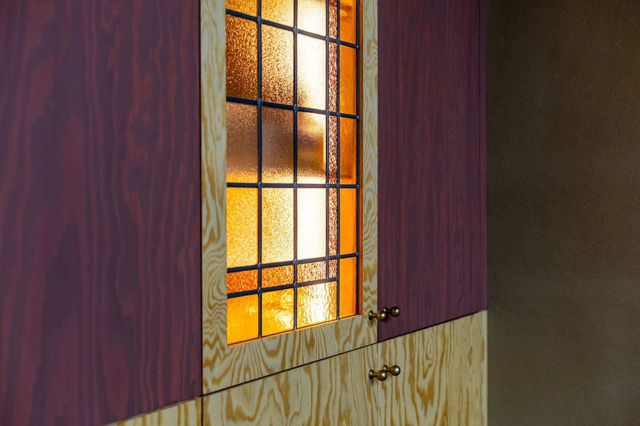Architectural project - vintage vibe, handcrafted feel, interior detail, heritage style, mood lighting, wooden cabinet, plywood finish, rustic cabinet, vintage cabinet, stained glass, glass panel, timber cabinet, mixed wood, colored glass, brass knobs, decorative glass, retro design, heritage vibe, accent piece, unique decor, crafted wood, bespoke furniture, art deco touch, artistic glass, warm setting, stained wood, polished finish, artistic panel, colorful glass, classic touch, interior warmth, detailed craftsmanship, decorative panel, stained glass panel, glass design, brass, intimate space, natural materials, wood, eclectic style, glass, warm tones, warm wood, cozy nook, wood grain, warm light, textured glass