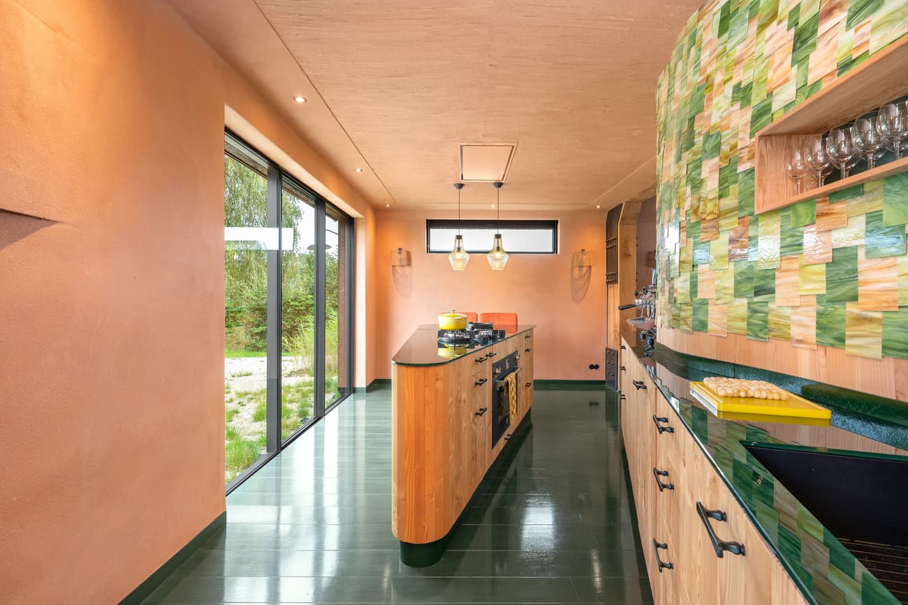 Architectural project - custom design, residential kitchen, pendant lights, green tiles, sleek cabinets, colorful kitchen, glazed tiles, orange walls, terrazzo countertop, handleless cabinets, contemporary lighting, artistic kitchen, eco-friendly design, sustainable materials, timber, playful design, natural light, glass, warm tones, neutral tones, functional space, daylight, light wood, Scandinavian style, minimalist style, glass doors, vibrant colors, creative space, eco home, sustainable home, indoor outdoor, large window, energy efficient, plaster, bright kitchen, open layout, panoramic view, inviting space, cozy atmosphere, garden view, modern kitchen, kitchen island, nordic influence, innovative materials, unique design, renovation, kitchen, ceramic tiles, remodel