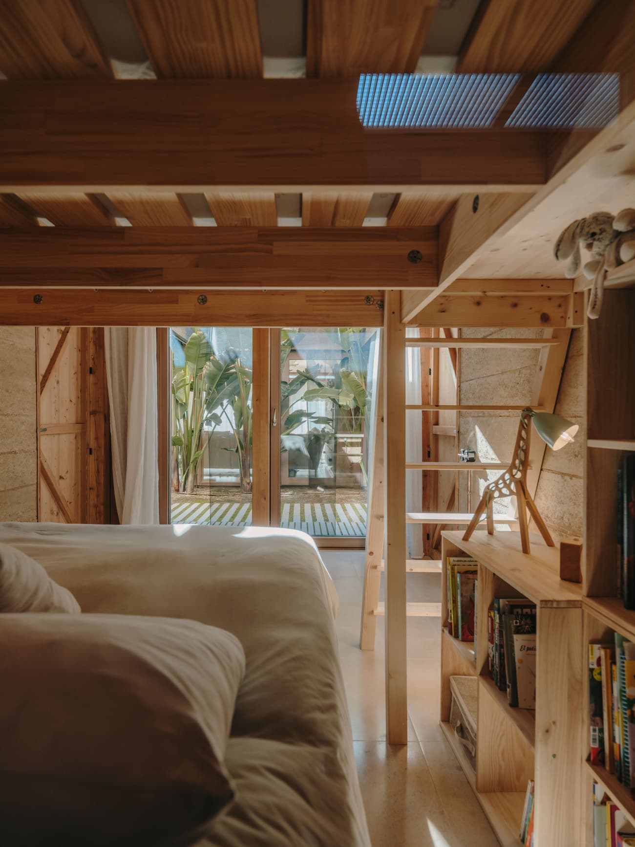 Architectural project - warm bedroom, green view, bedroom, loft bed, wooden loft, bamboo plant, tropical feel, balcony access, bedside lamp, comfortable bedding, home sanctuary, restful space, light filled room, natural materials, wood, timber, relaxed vibe, natural light, neutral tones, functional space, daylight, light wood, eco friendly, simple design, rustic vibe, honey wood, wood beams, timber beams, rustic modern, private retreat, Scandinavian style, soft textures, earth tones, modern rustic, sustainable home, Nordic style, beige tones, small space, inviting interior, compact design, timber shelves, open shelves, casual living, warm atmosphere, cozy corner, bright space, airy feel, cozy bedroom, linen, linen sheets, homey feel, indoor plants, reading lamp
