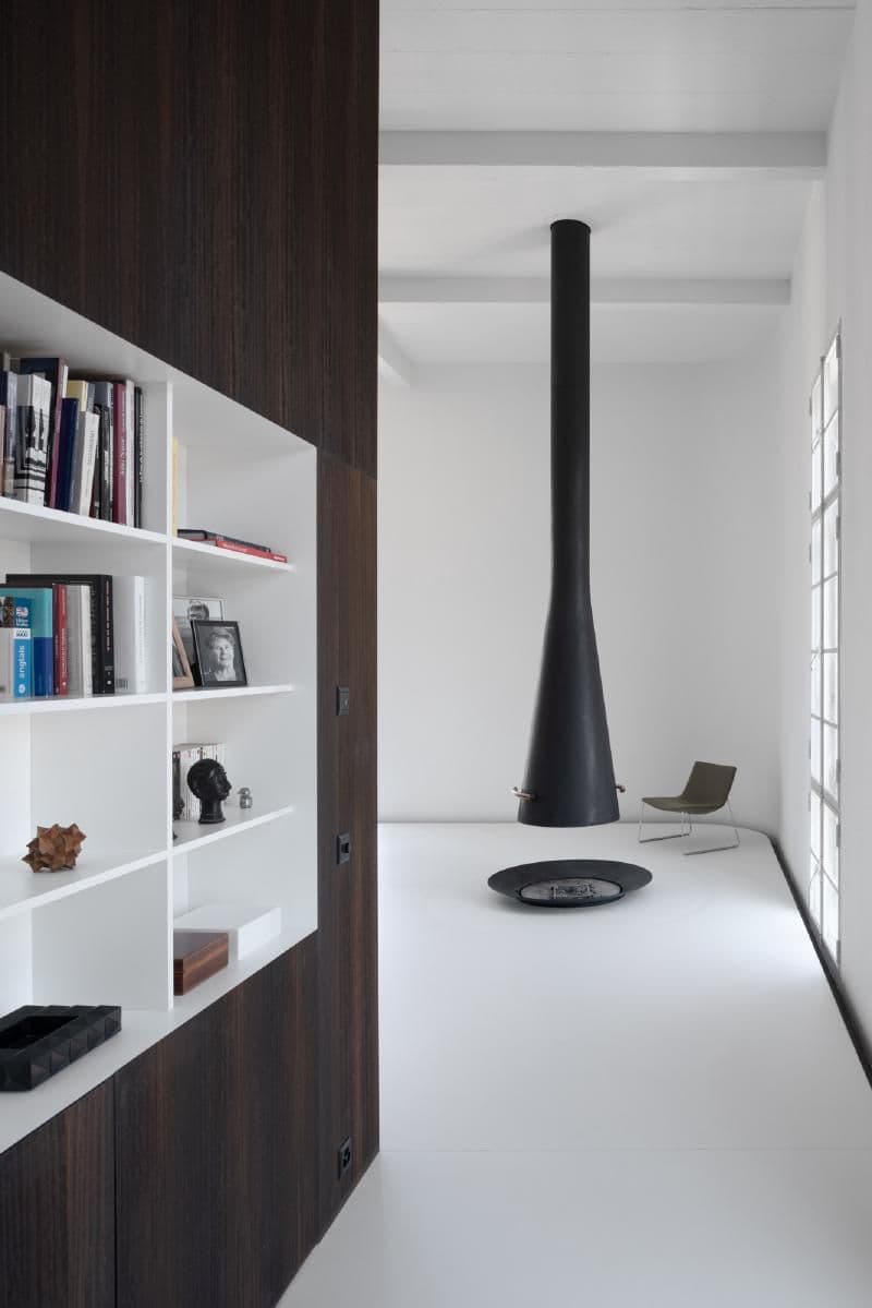 Architectural project - contrast design, minimalist living, artistic vibe, warmth, polished floor, sleek fireplace, cylindrical fireplace, white shelves, corner chair, contemporary chair, sleek interior, monochrome, statement fireplace, steel fireplace, inviting and serene, simplicity, function, style, interior sanctuary, modern elegance, black fireplace, calming atmosphere, relaxation area, natural light, functional space, Scandinavian style, neutral palette, minimalist design, geometric design, clean lines, white walls, light filled, architectural simplicity, Nordic design, open shelves, airy space, open plan, minimalist decor, cozy corner, reading nook, reading area, lounge chair, bright interior, modern home, spacious living, cozy home, modern interior, built-in shelving, modern retreat, living space, architectural lines, versatile space, architectural feature, black and white