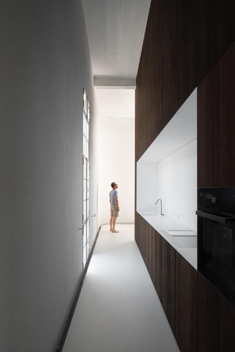 Architectural project - micro-living, small space living, apartment kitchen, monochrome palette, recessed lighting, refined design, white countertop, narrow kitchen, corridor kitchen, white surfaces, integrated appliances, limited space, sleek kitchen, luxury finish, urban kitchen, stylish kitchen, modern elegance, high contrast, polished interior, narrow corridor, wood, timber, contemporary style, neutral tones, functional space, modern design, minimalist vibe, minimalist style, clean lines, timber cladding, wood cladding, white, modern architecture, cozy atmosphere, minimalist kitchen, sleek design, compact kitchen, efficient layout, interior design, home renovation, dark tones, efficient design, residential interior, dark wood, vertical space, high ceiling, urban living, light flooring, hallway design