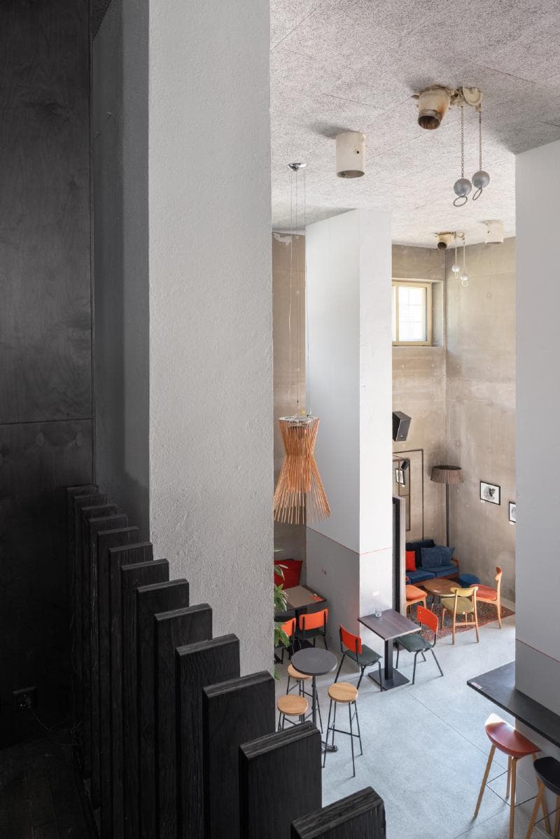 Architectural project - exposed concrete, casual vibe, modern decor, urban cafe, concrete ceiling, concrete walls, vintage chairs, raw interior, colorful chairs, industrial cafe, loft cafe, wicker lamp, eclectic furniture, playful seating, community zone, black accents, mix and match, cafe setting, modern cafe, sustainable materials, wood, natural light, rustic touch, natural tones, eco design, grey, daylight, concrete, industrial style, functional design, Scandinavian influence, black, social space, gathering area, vibrant colors, open plan, minimalist decor, cozy atmosphere, textured walls, bright space, interior, concrete floor, contemporary vibe, pendant light, warm lighting, indoor, artistic space, versatile space, high ceiling, double height, urban style, wicker, urban interior