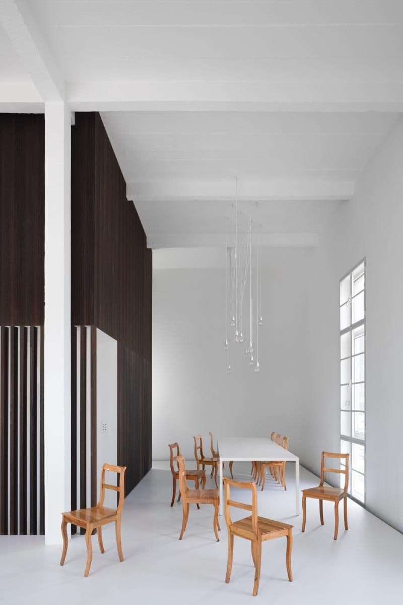 Architectural project - modern decor, airy interior, modern dining, simple table, pendant lighting, spacious vibe, minimalist dining, wood chairs, timber details, modern elegance, tall windows, white dining room, minimalist table, dark accent wall, table setting, dining setup, stylish simplicity, elegant chairs, indoor space, soft lighting, wood, neutral tones, functional space, brown, light wood, Scandinavian influence, architectural lighting, serene atmosphere, minimalist style, clean lines, white walls, light filled, white, Nordic design, open layout, open plan, residential design, wooden seating, modern home, sleek design, wooden accents, residential area, vertical panels, contemporary space, interior architecture, high ceiling, bright room