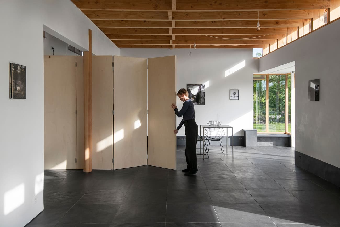 Architectural project - natural materials, eco-friendly design, wood, raw materials, grey, natural light, warm tones, exposed beams, daylight, plywood, timber ceiling, beige, concrete, light wood, multifunctional space, modern design, Scandinavian style, minimalist style, neutral palette, casual seating, biophilic design, sustainable home, clean lines, white walls, large windows, Nordic design, open plan, living area, simple living, outdoor connection, garden view, residential space, minimal interior, wood ceiling, folding partition, pivot door, concrete floor, dark tiles, floor-to-ceiling window, interior space, home interior, family room, contemporary aesthetic, open space, cozy home, airy atmosphere, black tiles, oak