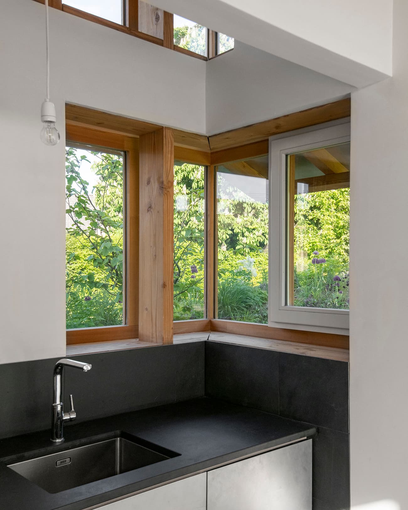 Architectural project - eco-friendly design, timber, timber frame, natural light, passive design, glass, light wood, natural wood, daylight optimization, Scandinavian influence, compact space, sunlight, neutral palette, black, relaxed atmosphere, sustainable home, clean lines, white walls, indoor outdoor, white, window view, stone, plaster, green living, cozy kitchen, inviting space, garden view, wood trim, bright interior, minimalist kitchen, modern kitchen, efficient layout, fresh air, plaster walls, corner kitchen, small kitchen, kitchen sink, sleek faucet, inside outside, wooden accents, black countertop, stone counter, minimal decor, open window, greenery view, functional kitchen, simple style, contemporary vibe