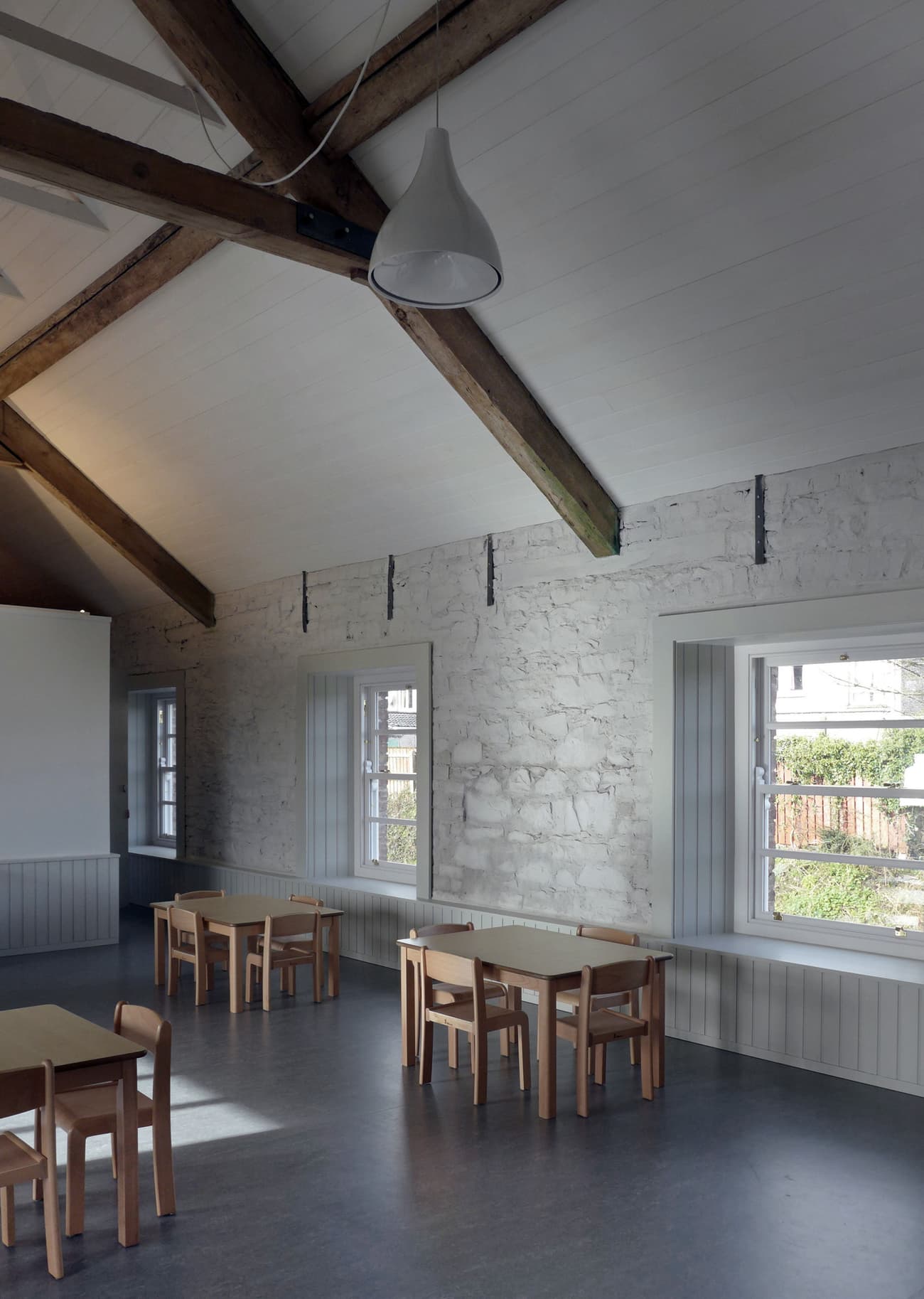 Architectural project - stone walls, modular furniture, meeting space, inviting vibe, wood, timber, natural light, sustainable design, eco design, grey, neutral tones, exposed beams, daylight, wooden ceiling, beige, light wood, multifunctional space, rustic modern, calm ambiance, neutral palette, minimalist design, gathering area, community center, event space, eco-friendly materials, workshop area, modern rustic, passive house, white walls, white, Nordic style, stone, cozy atmosphere, textured walls, Scandinavian design, educational space, simple furniture, pendant lamp, family-friendly, high ceiling, pitched ceiling